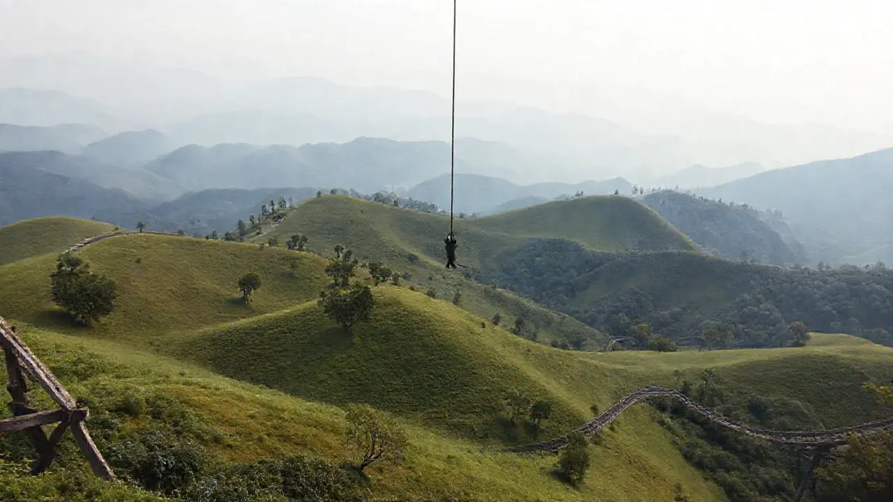 Paisaje extenso, montañas, y una figura suspendida