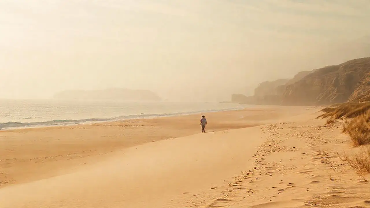 Playa serena, luz dorada y figura distante