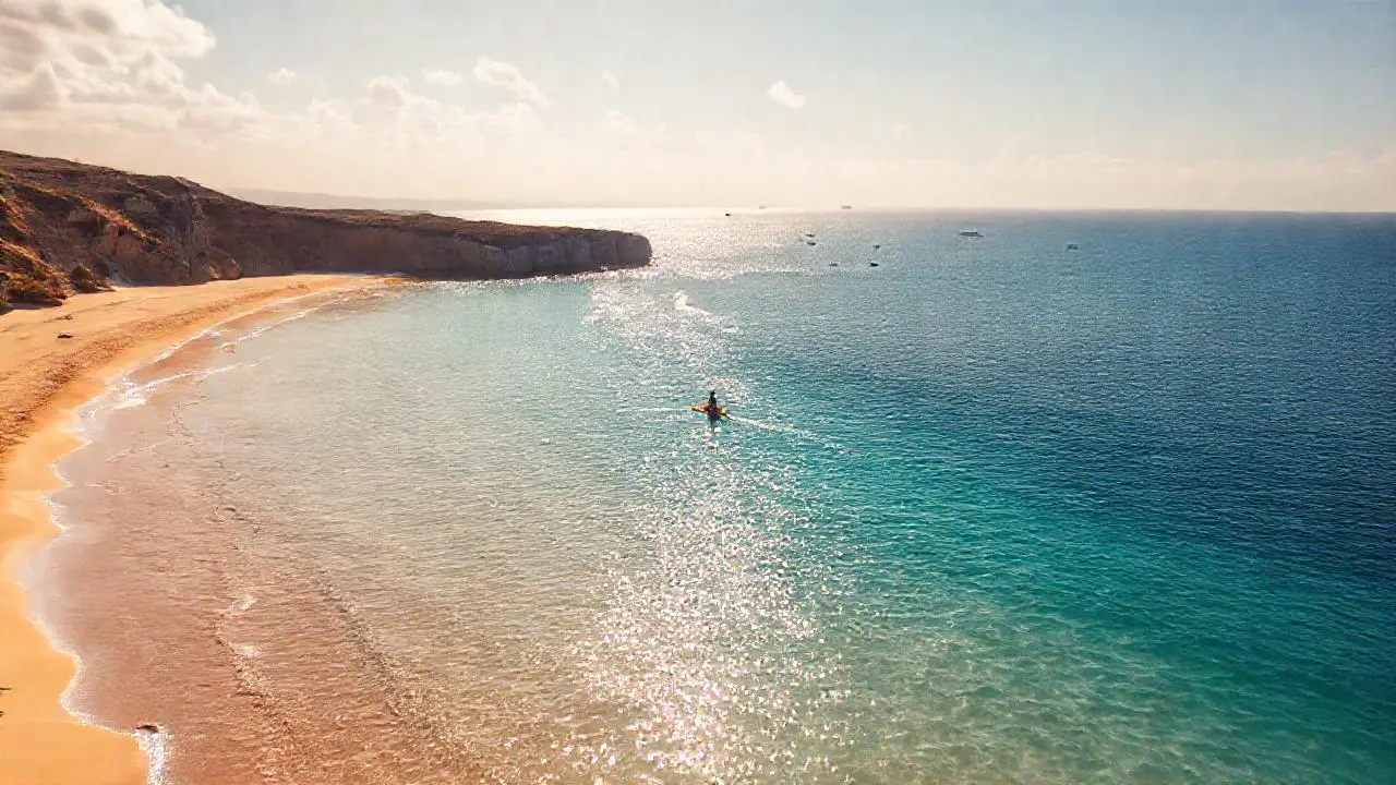 Costa serena, luz dorada, kayakista solitario