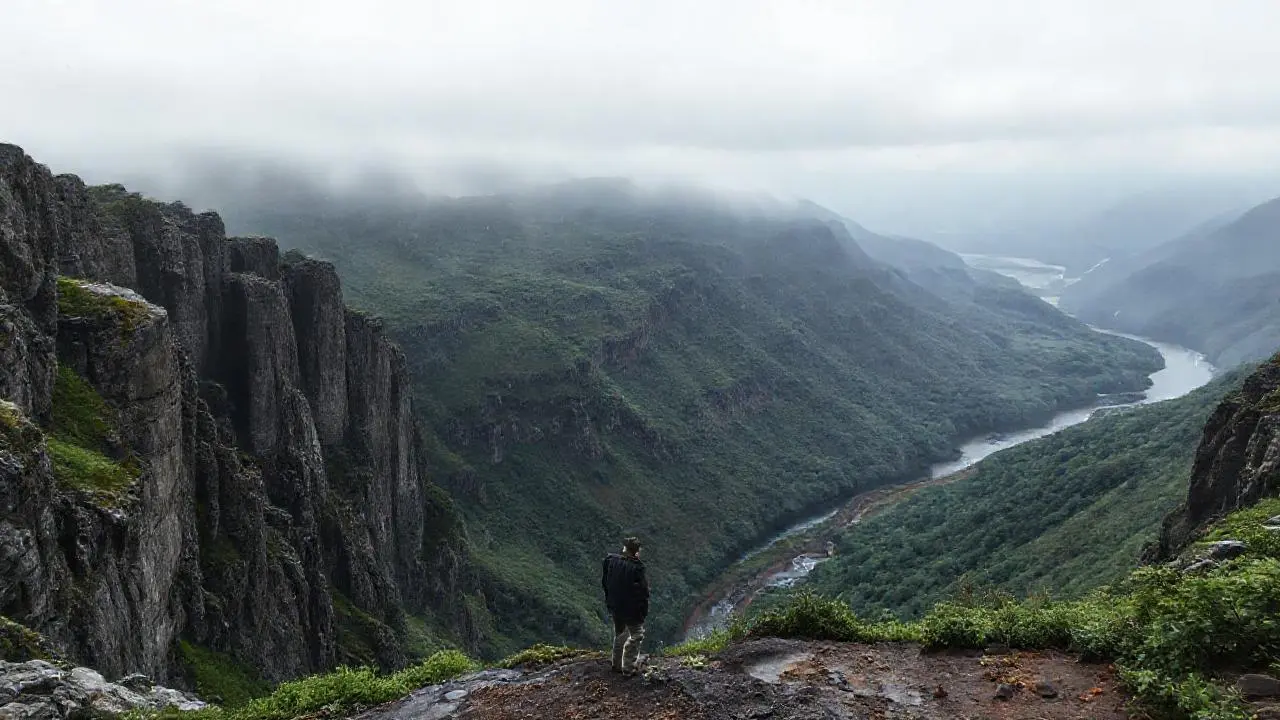 Paisaje húmedo y montañoso, con figura solitaria