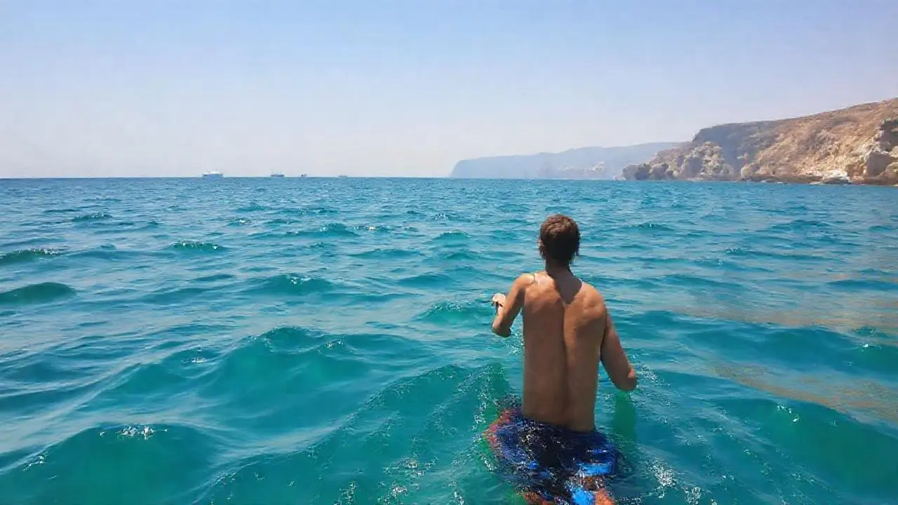 Aguas tranquilas, sol, y una figura nadando