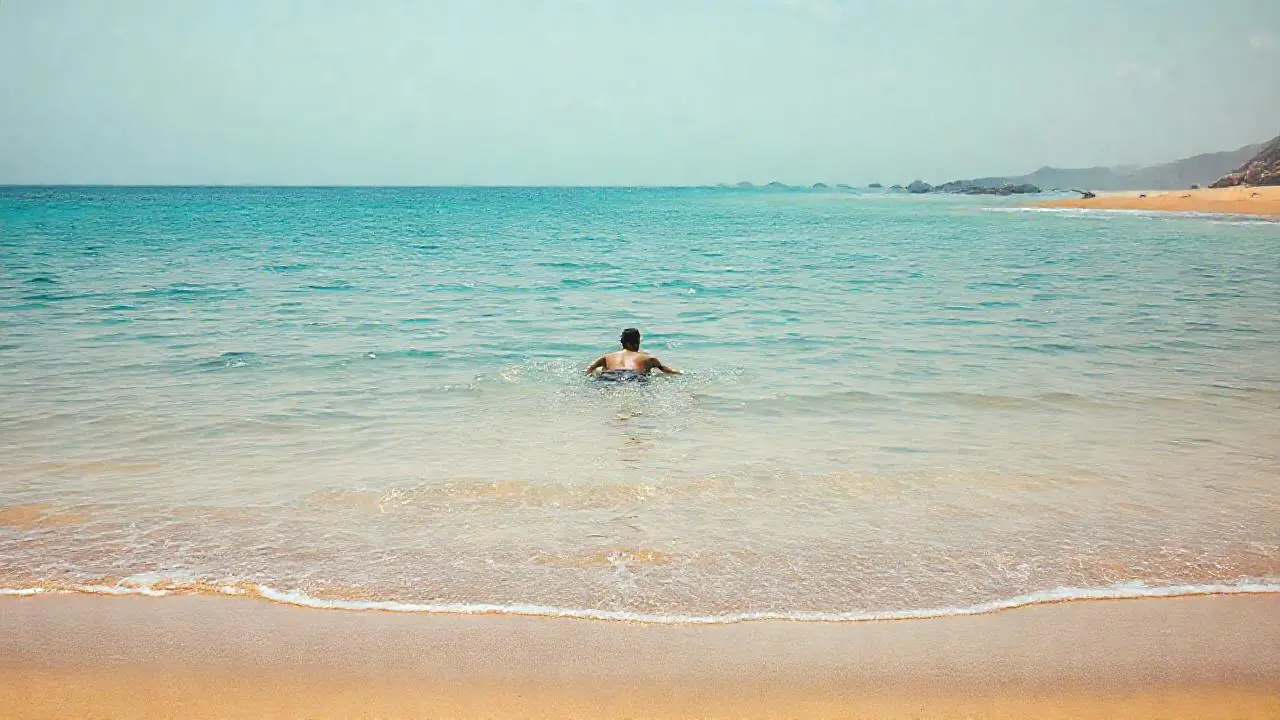 Playa tranquila, luz cálida y nadador sereno