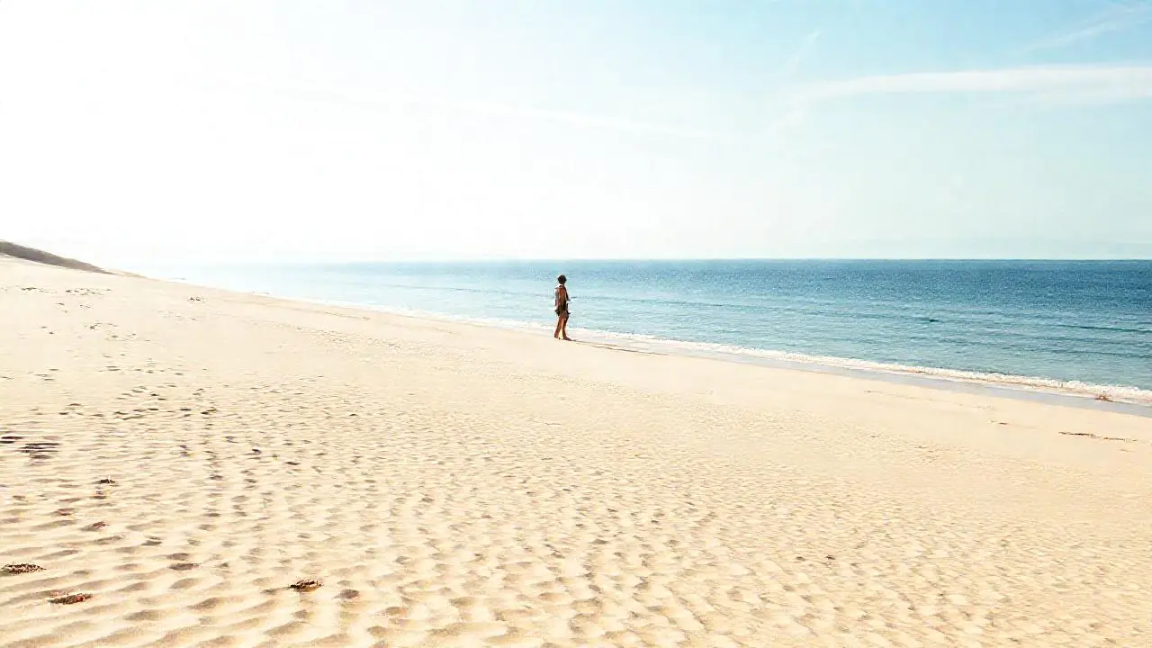 Playa tranquila, luz suave, horizonte amplio