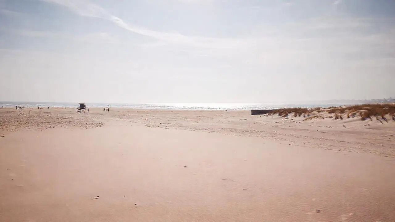 Playa extensa, tranquila y ligeramente brumosa